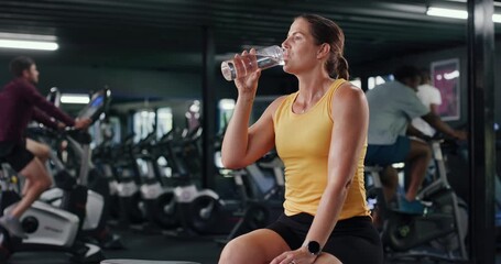 Woman, drinking water and fitness with hydration in gym for rest, recovery or workout break. Thirsty, active female person or mineral liquid with aqua, bottle or beverage for nutrition in health club - Powered by Adobe