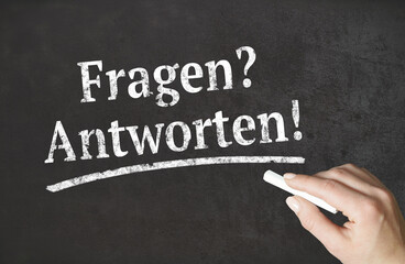 „Fragen? Antworten!“ Wort mit Kreide auf einer Tafel