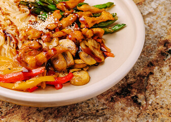 Colorful stir-fried vegetables with chicken and noodles on a plate