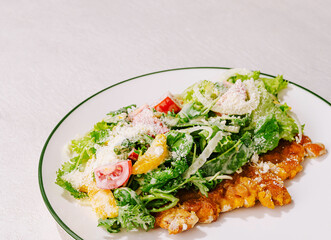 Fresh salad with greens, tomatoes, and cheese on a white plate