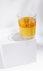Refreshing orange drink in clear cup on white pedestal
