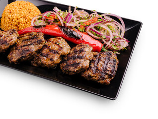 Grilled meat platter with bulgur and fresh salad on a black plate