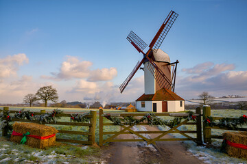 Naklejka premium Historic English windmill in a festive winter landscape with snow and Christmas decorations