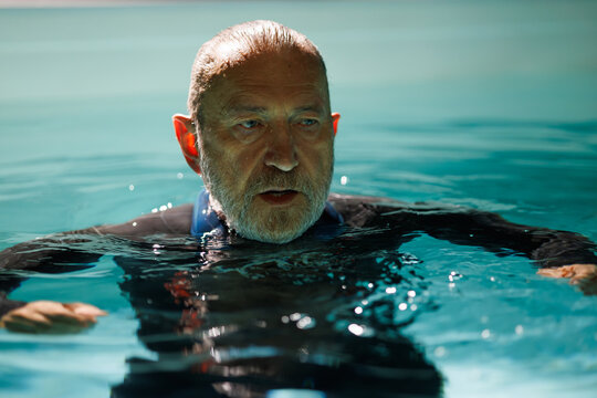 Senior diver in wetsuit and neck weight standing in swimming pool  - Powered by Adobe