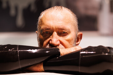 Grey haired free diver in wet suit looking at camera in swimming pool 