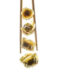 Four delicious dumplings are held vertically by wooden chopsticks against a bright white background.