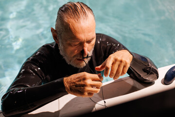Senior diver in swimwear wearing nose clip at poolside 
