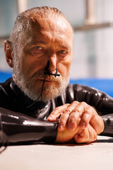 Portrait of senior diver in wetsuit and nose clip looking at camera on poolside 