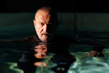 Portrait of senior free diver looking at camera from swimming pool 