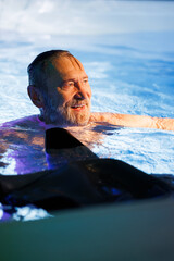 Cheerful senior diver swimming near wetsuit in pool