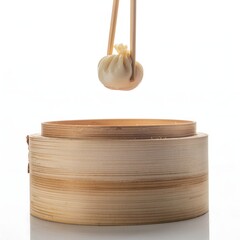 A single dumpling is held aloft by chopsticks, positioned above a bamboo steamer.
