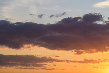 Sunset sky beauty, Calm evening with colorful clouds, Bright orange horizon with dark clouds contrasting, Peaceful twilight scene featuring layered clouds and soft blue sky