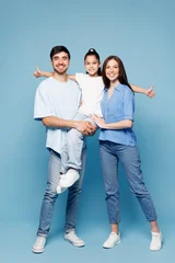 Fototapeten Pony Full body young smiling fun happy parents mom dad with child kid girl wearing casual clothes hold daughter in hands look camera hugging isolated on plain blue background. Family day childhood concept.  © ViDi Studio