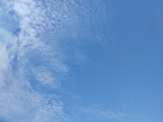 clear blue sky with a few clouds. The sky is very bright and the clouds are scattered throughout. Copy space 