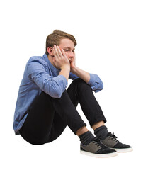 Upset and puzzled teenage guy sitting on the floor keeps hands under chin looks thoughtful away. Difficult decisions, life questions and hesitations. Melancholic adolescent full length seated portrait