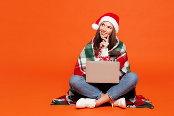 Full body merry young IT woman she wear cozy plaid red Christmas Santa hat posing hold use work on...