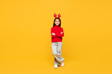 Full body merry little girl wear red clothes decorative deer horns on head posing hold hands...