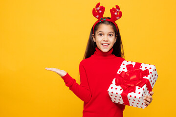 Merry shocked little girl wear red clothes fun decorative deer horns on head posing present box...