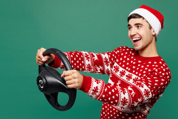 Side view merry young student man wears red cozy Christmas sweater Santa Claus hat posing hold...