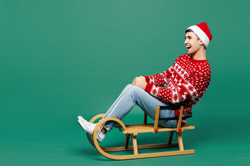 Full body side profile view merry cool young man wear red warm cozy Christmas sweater Santa Claus...