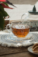 Christmas tea party. Cup of warm tea on rustic table, cozy atmosphere in background.