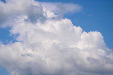 Fluffy, soft white clouds drift peacefully against a bright blue sky on a calm day