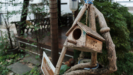 A quaint wooden birdhouse hanging from a tree branch, with intricate details, blending into a serene outdoor setting.