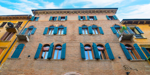 Verona, Italy. Traditional colorful building with balconies, shutter windows and multicolored walls in typical italian street