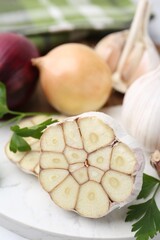 Garlic, onions, and parsley on white table, closeup