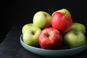 Fresh red and green apples on dark textured table against black background, closeup. Space for text
