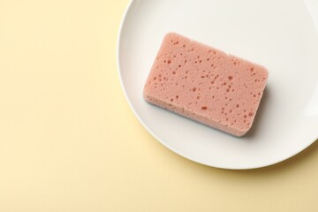 Kitchen sponge and plate on beige background, top view. Space for text