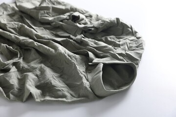 Green creased shirt on light background, closeup