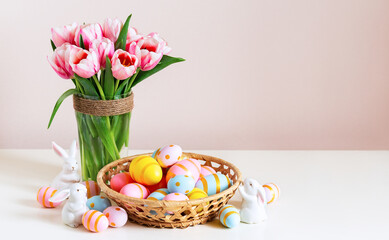 Easter holiday decorating with painted eggs in the basket on wooden table and beautiful spring flowers. Happy easter background with copy space.