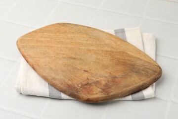 Wooden cutting board on white tiled table, closeup