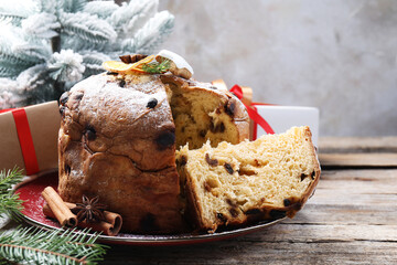 Tasty Christmas panettone cake with powdered sugar and festive decor on wooden table, closeup