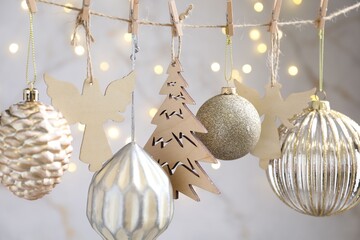 Fototapeta premium Beautiful Christmas decor hanging on string against blurred lights, closeup