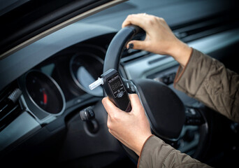 Female Driver Holding Breathalyzer And Steering Wheel. Deciding About Safe Driving After Test.