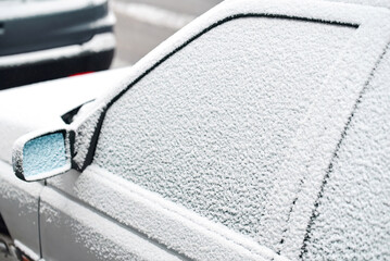 Parked car with its side window completely covered in fresh winter snow, freezing temperatures...