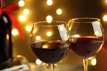 Glasses of red wine against blurred lights, closeup. Christmas and New Year celebration