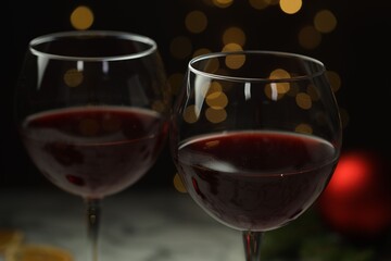 Glasses of red wine against blurred lights, closeup. Christmas and New Year celebration