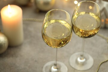 Glasses of white wine and Christmas decor on gray table, closeup