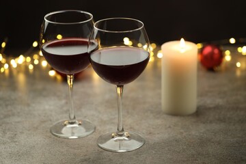 Glasses of red wine and Christmas decor on gray table, closeup