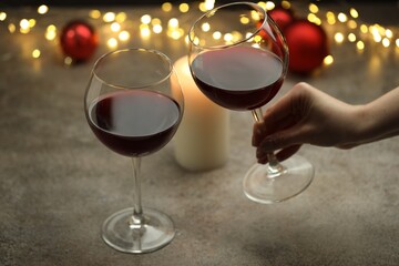 Woman with glass of red wine at gray table, closeup. Christmas and New Year celebration