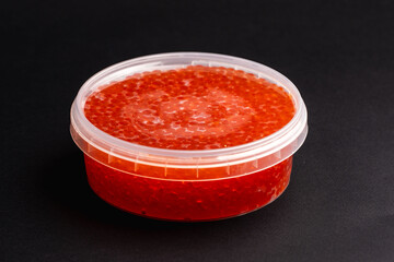 Red Salmon Roe (Ikura) in Plastic Container on Black Background