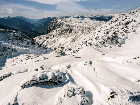 Snowy mountain landscape with distant peaks and a valley below, under a blue sky. Paganella, Roda refuge,Trentino, Italy