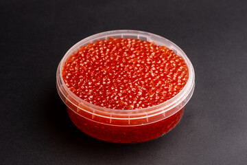 Red Salmon Roe (Ikura) in Plastic Container on Black Background