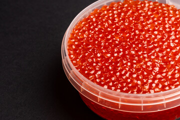 Red Salmon Roe (Ikura) in Plastic Container on Black Background