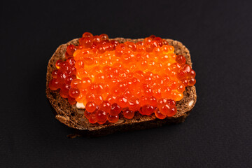 Red Salmon Roe (Ikura) in Plastic Container on Black Background