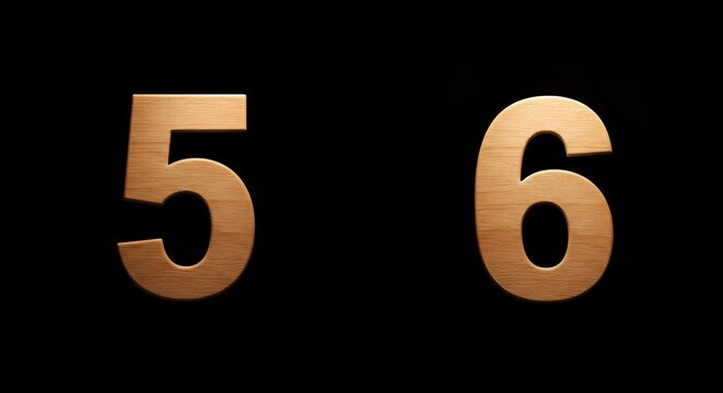 Wooden number five and six stand side-by-side on a solid black background, minimal and isolated.
