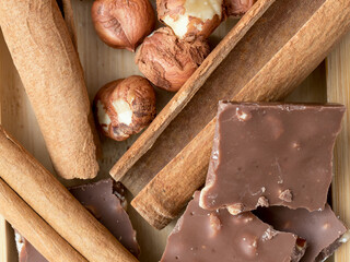 Hazelnuts, cinnamon, chocolate with nuts, background, Christmas wallpaper on a wooden countertop, close-up view, healthy unsaturated fats, spices, plant protein, fiber, vitamins and minerals
